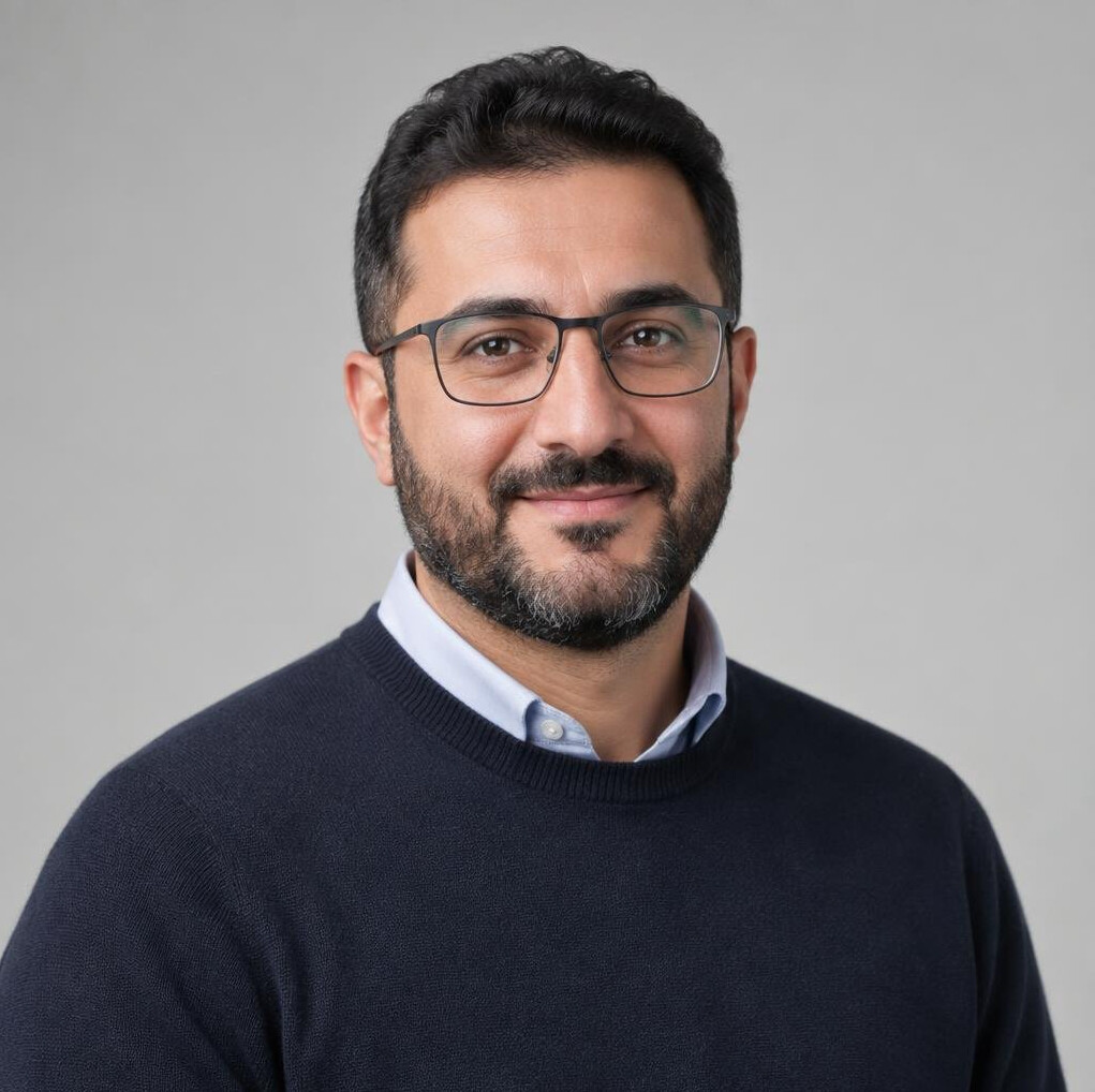 Studio portrait of a Middle Eastern man with a beard and glasses